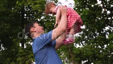 快乐的爸爸抱着他心爱的女儿在她的<strong>怀里</strong>亲吻她的脸颊和微笑。