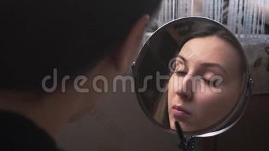 美丽的女孩照镜子，用铅笔<strong>画眉</strong>毛，化妆。