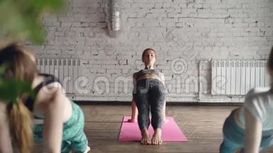 女瑜伽老师展示了向上的木板姿势Purvottanasana，并在她的学生重复的时候讲述了这一点