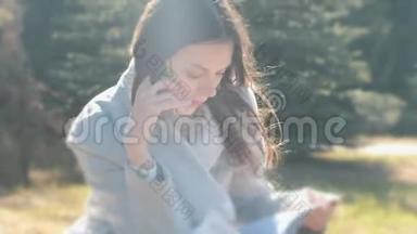 布尼斯女人坐在<strong>春天</strong>公园的草地上，用<strong>手机</strong>说话的肖像。