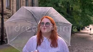戴眼镜的胖姜女孩在雨天的<strong>公园里散步</strong>，撑着伞，思考着概念