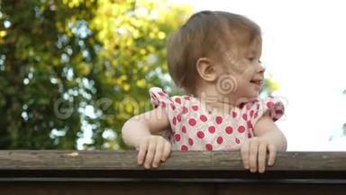 小快乐的<strong>宝宝</strong>笑着，第一颗<strong>牙齿</strong>在公园的长凳上玩耍，在博基的背景下。