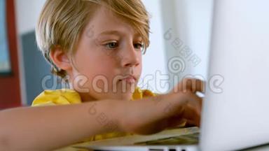 可爱的白人学生坐在桌子上，在教室里使用笔记本电脑