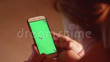 带绿色屏幕和跟踪点的女孩手持手机的背面视图
