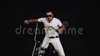 戴太阳镜的白衣男子坐在自行车上，按下刹车，转动车把