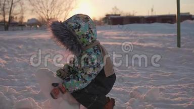 一个小孩在冬天的公园里玩雪.. 阳光明媚的冬天`白天。 新鲜空气中的乐趣和游戏。