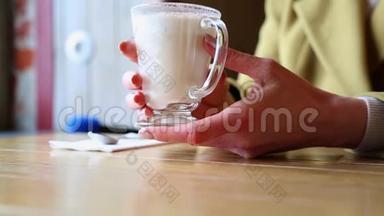 装有<strong>热</strong>泡<strong>牛奶</strong>的玻璃烧杯.. 女人在咖啡馆里把手放在一杯<strong>热牛奶</strong>上。 带着漂亮的拿铁