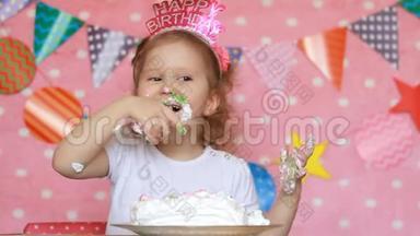 生日快乐。 一个可爱的小女孩吃了一个美味的蛋糕，微笑着，露出肮脏的脸和手。 一个孩子在吃