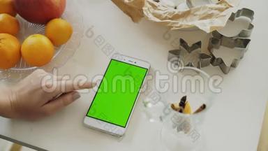`家厨房餐桌上有绿色屏幕的女士<strong>手游</strong>智能手机特写