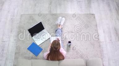 从上面看学生女孩坐在地毯上写在笔记本上。