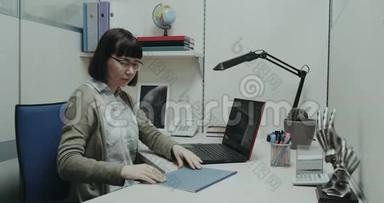 办公室里的一位年轻女士正在整理文件，敲敲键盘
