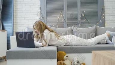 年轻的白种人女孩，有智能手机，躺在床上，上网，玩得很开心，很放松