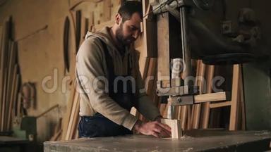<strong>木匠</strong>店。 一个漂亮的工人用<strong>电锯</strong>机从木块上切割一个带肋的形状。 评价工作