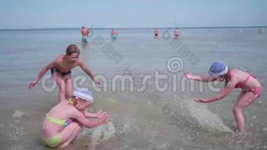 两个女孩和一个男人在海滩上泼水。 在炎热的夏日里，双胞胎泼水，欢笑和良好的心情