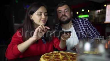 酒吧里的女孩在你的智能手机上拍披萨。