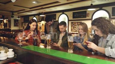 年轻人坐在酒吧<strong>柜台</strong>边看智能手机。 他们互相<strong>展示</strong>屏幕