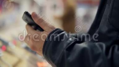 一个年轻人`商店里挑选一部新手机的特写镜头。 他在尝试它的运作方式