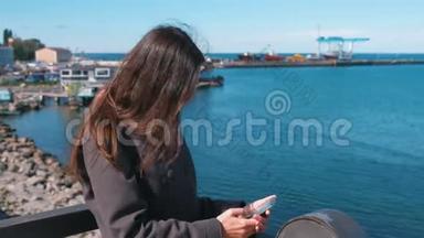 在阳光明媚的秋日，布吕内特女士在<strong>海边</strong>的<strong>海边</strong>，用手机输入一条信息。