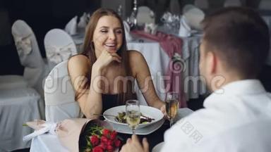 穿着漂亮衣服的开朗的女孩和男朋友说话，在餐馆一起吃饭时大笑
