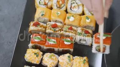 筷子的特写镜头将寿司卷在盘子或拼盘上。在日本酒吧餐厅提供。顶部