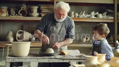 关心的老爷爷正在向小孙子展示如何在小作坊里用粘土做投掷轮。 陶器