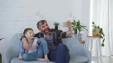 有趣的男人爱父亲正在和他开朗的儿子自拍，笑着打手势，摆姿势拍照。 自画像