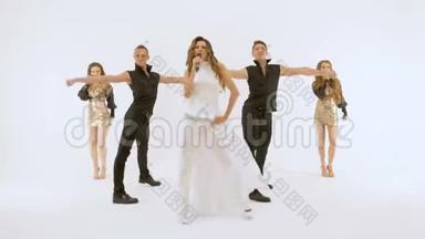音乐视频的视频拍摄.. 穿白色连衣裙的女歌手两个穿黑色西装的年轻人在跳舞。 两个漂亮的