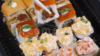 <strong>筷子</strong>的特写镜头将寿司卷在<strong>盘子</strong>或拼盘上。在日本酒吧餐厅提供。顶部