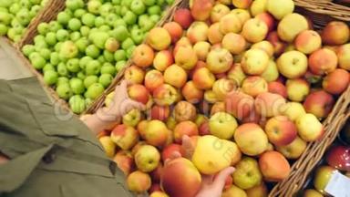 一个女人在蔬菜货架上的<strong>超市</strong>里买蔬菜和<strong>水果</strong>。 人类选择苹果。 慢动作，4k