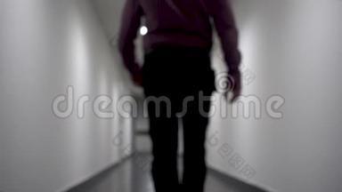 一个人沿着长长的白色走廊走去。 背景模糊。 视频包含闪烁和噪声..