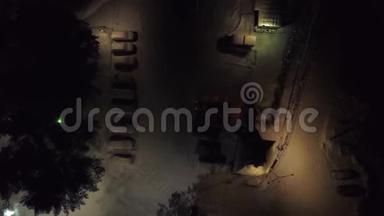 冬季夜间停车场的俯视图。 剪辑。 城市停车场，冬季夜间有积雪覆盖的汽车和昏暗的灯光