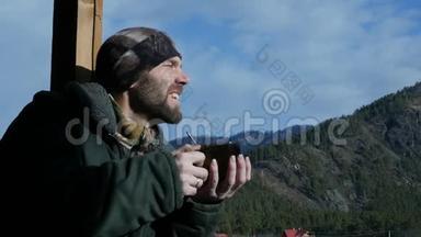 寂寞的胡须男站在观察甲板上看着一座山，喝着<strong>大杯子</strong>里的咖啡或茶。 慢慢慢慢
