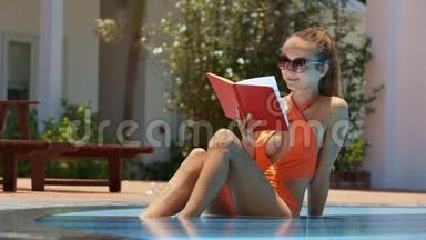 度假酒店游泳池里的金发女士阅<strong>读书籍</strong>