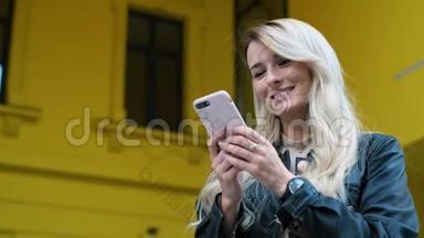 女士和使用智能手机户外。 漂亮的时髦女郎，学生女孩在黄色手机上发短信和使用应用程序