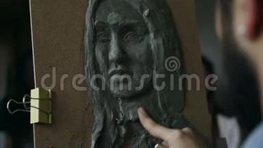 雕塑家的特写镜头在艺术工作室的画布上创作人`的面部雕塑
