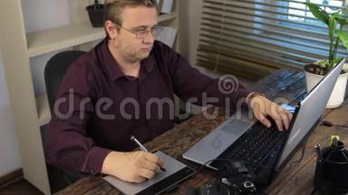 平面设计师，在办公室使用笔记本电脑时绘制图形平板电脑。