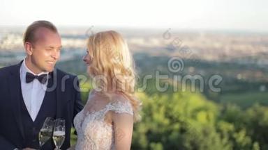 新郎和<strong>新娘</strong>站在城市的背景上，喝着酒杯里的香槟。 克林克眼镜。 Hd<strong>视频</strong>