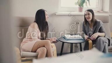 两个漂亮的欧洲女人坐着非正式地交谈。 办公室职位的面试。 商务教练培训课程