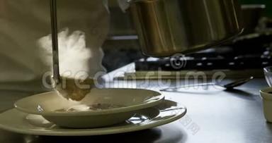 女厨师用勺子把汤倒入厨房的盘子里
