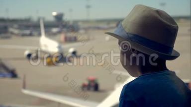 一个男孩看着机场的<strong>飞机跑道</strong>等待旅行，关闭。