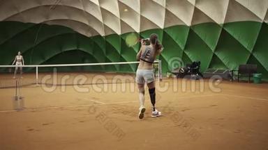 两个穿着<strong>运动</strong>服和胸罩的漂亮高个子女孩在打网球。 印支。 移动<strong>摄像机</strong>
