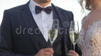 新郎和新娘站在城市的背景上，喝着酒杯里的香槟。 克林克眼镜。 Hd视频