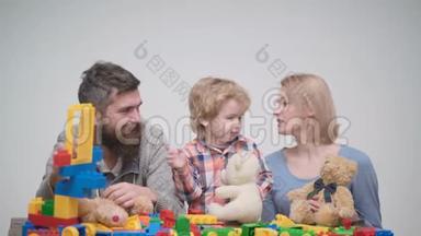 年轻的家庭玩游戏与建筑塑料块。 家庭游戏的概念。 父母和孩子的脸都红<strong>了</strong>