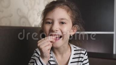一个可爱的小女孩摇摇晃晃地摇晃着她松动的牙齿，想把它拔掉