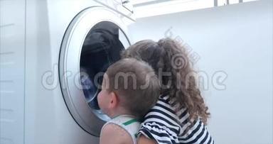 可爱的孩子们在洗衣机里看。 气缸旋转机。 概念洗衣机，工业