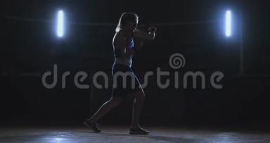 训练一个漂亮的女拳击手在黑暗的房间里打拳。 斯坦迪卡姆。 自卫和战斗准备