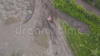 在一个有沙面和乡村道路的建筑工地上，一辆尖头卡车驶往装载沙子和土壤的高空俯视图