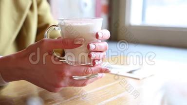 装有<strong>热</strong>泡<strong>牛奶</strong>的玻璃烧杯.. 女人在咖啡馆里把手放在一杯<strong>热牛奶</strong>上。 带着漂亮的拿铁