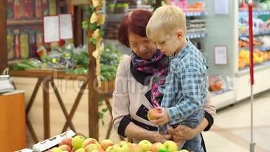 一位老年妇女带着她的小孙子在大型超市买新鲜<strong>苹果</strong>。