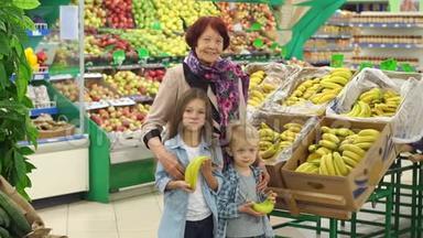 快乐的老妇人带着孙子在超市买水果。 肖像。